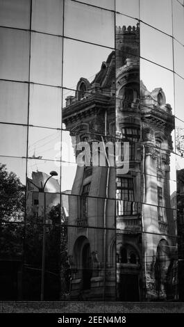 Senkrechte Graustufenaufnahme der Gebäudespiegelung auf dem Glas Gebäude in Bucarest Stockfoto