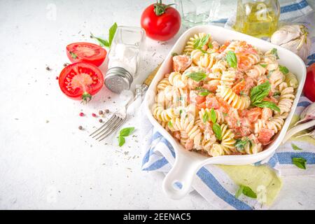 Frühlingsdiät gesunde vegane Pasta. Italienische Fusilli Pasta mit Tomaten, grünem Gemüse, frischen Kräutern, Frischkäse oder Feta, auf weißem Tischhintergrund c Stockfoto