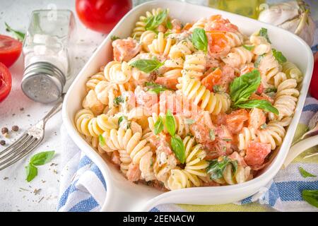 Frühlingsdiät gesunde vegane Pasta. Italienische Fusilli Pasta mit Tomaten, grünem Gemüse, frischen Kräutern, Frischkäse oder Feta, auf weißem Tischhintergrund c Stockfoto