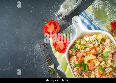 Frühlingsdiät gesunde vegane Pasta. Italienische Fusilli Pasta mit Tomaten, grünes Gemüse, frische Kräuter, Frischkäse oder Feta, auf dunklen Tisch Hintergrund Co Stockfoto