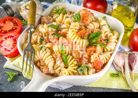 Frühlingsdiät gesunde vegane Pasta. Italienische Fusilli Pasta mit Tomaten, grünes Gemüse, frische Kräuter, Frischkäse oder Feta, auf dunklen Tisch Hintergrund Co Stockfoto