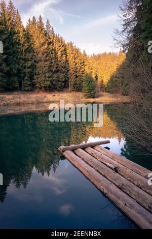 Friedlicher Sonnenuntergang auf einem kleinen See mitten im Wald. Bäume spiegeln sich auf der Wasseroberfläche. Herbstabend in den Bergen. Stockfoto