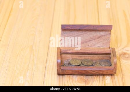 Hölzerne Schatzkiste mit ein paar Münzen auf Holzhintergrund. Konzept des Geldverdienen - Geschäft und so weiter. Stockfoto