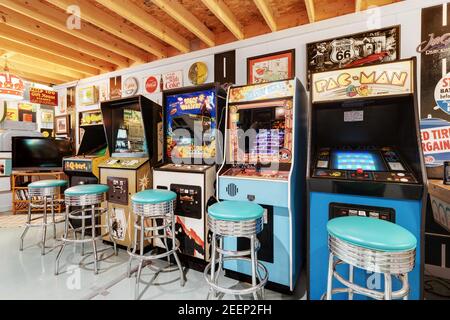 Eine Kellerhalle mit verschiedenen Retro-Flipper und klassischen Arcade-Spielen, alten Stahl- und Blechschildern und vielen Sitzgelegenheiten. Stockfoto