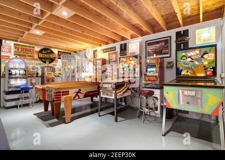 Eine Kellerhalle mit verschiedenen Retro-Flipper und klassischen Arcade-Spielen, alten Stahl- und Blechschildern und vielen Sitzgelegenheiten. Stockfoto