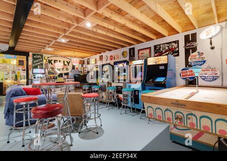 Eine Kellerhalle mit verschiedenen Retro-Flipper und klassischen Arcade-Spielen, alten Stahl- und Blechschildern und vielen Sitzgelegenheiten. Stockfoto