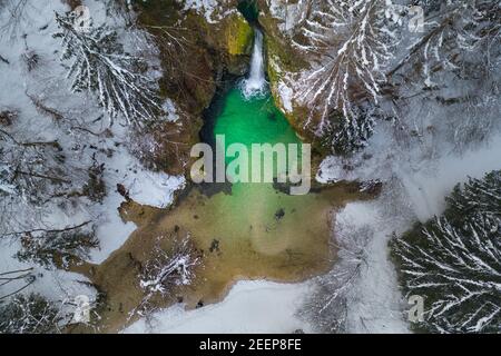 Winterszene mit kleinem Wasserfall mit Schnee im Naturwald. Stockfoto