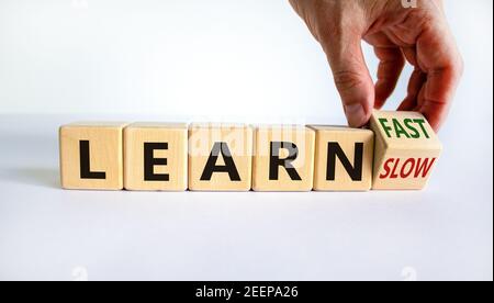 Lernen Sie langsam oder schnell Symbol. Geschäftsmann dreht Holzwürfel und ändert die Worte "langsam lernen" zu "schnell lernen". Schöner weißer Hintergrund, Kopierbereich. Busi Stockfoto