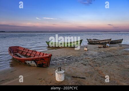 Fischerboote aus Holz am Ufer / Ufer des Flusses Paraná / Río Paraná im Dorf Yahapé bei Sonnenuntergang, Iberá NP, Corrientes, Argentinien Stockfoto