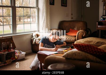 Mädchen homeschooling im Wohnzimmer mit Hund schlafen im Hintergrund Stockfoto