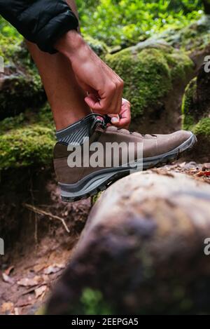 Nahaufnahme junger Mann, der beim Trekking ihre Schuhe bindet Stockfoto
