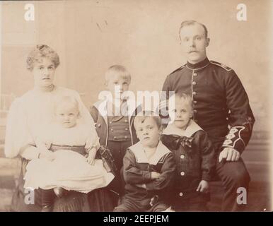 Vintage Fotopostkarte aus dem frühen 20. Jahrhundert zeigt einen Militärmenschen mit seiner Frau und seinen Kindern. Stockfoto