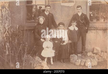 Jahrgang Anfang 20th Jahrhundert fotografische Postkarte zeigt eine Familie Gruppe posiert in ihrem Garten. Stockfoto