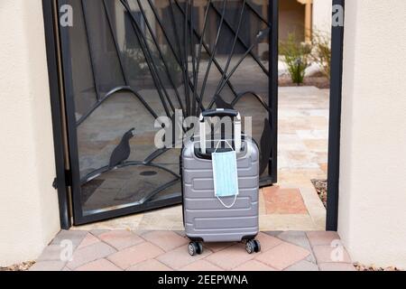 Öffnen Sie das Tor vom Innenhof mit Koffer und Gesichtsmaske Frontshow Coronavirus Pandemie Reisevorbereitung und Bereitschaft Stockfoto