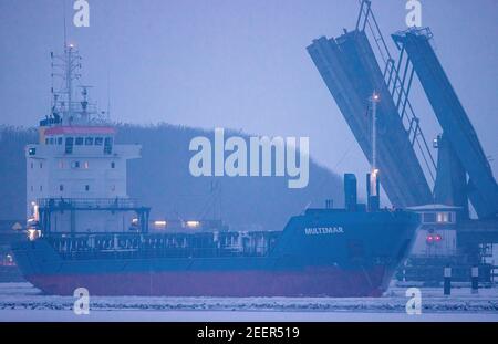 Stralsund, Deutschland. Februar 2021, 16th. Das Frachtschiff Multimar passiert am Abend die offene Ziegelgraben-Brücke zwischen dem Festland und der Insel Rügen. Das eisige Wetter der letzten Tage hat in Mecklenburg-Vorpommern auf den Boddengewässern der Ostsee eine Eisschicht verursacht. Quelle: Jens Büttner/dpa-Zentralbild/dpa/Alamy Live News Stockfoto