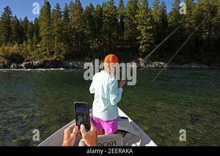 Joanne Linehan hakt eine große Forelle, während ihr Mann Tim ein Handy-Foto auf dem Kootenai River macht. Lincoln County, MT. (Foto von Randy Beacham) Stockfoto