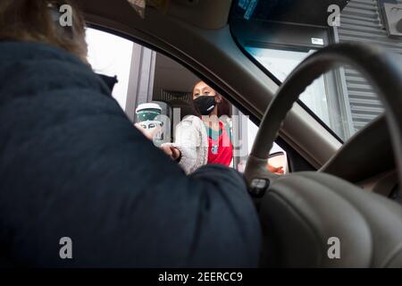 Der Gast, der während der Covid-Pandemie Kaffee vom Server am Starbucks Drive-Thru-Fenster mit Masken empfing. St. Paul Minnesota, USA Stockfoto