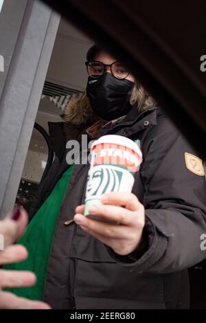 Maskierter Kaffeeservice, der einem Gast im Starbucks Drive-Thru eine Tasse in einem Auto überreicht. St. Paul Minnesota, USA Stockfoto