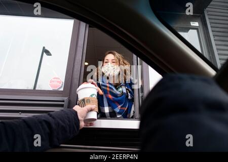 Maskierter Starbucks Drive-Thru-Kaffeeservice, der einem Gast im Auto während der Covid-Pandemie einen Kaffee überreicht. St. Paul Minnesota, USA Stockfoto