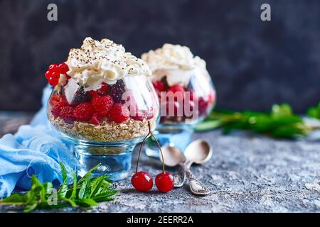 Rezeptideen für eine sommerliche Diät Frühstück, gesundes Morgendessert in portionierten Gläsern mit Sommerbeeren - Himbeere, Kirsche, Brombeere. Auf steinernem Hintergrund. Stockfoto