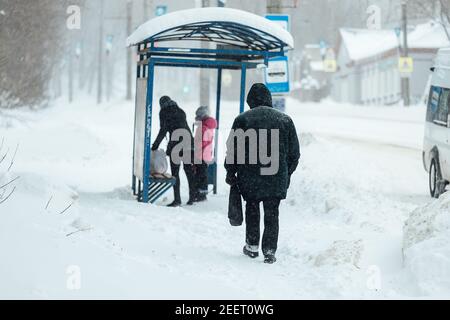 Ein Mann mit Schwierigkeiten geht durch tiefen Schnee, Schneeverwehungen auf dem Bürgersteig nach einem starken Schneefall. Schlechter Betrieb der öffentlichen Versorgungsunternehmen im Winter Stockfoto