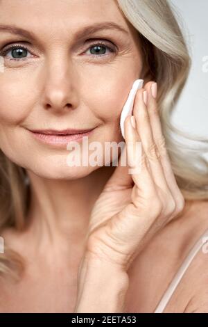 Ziemlich 50s Frau mittleren Alters hält Baumwolle Schwamm Reinigung Gesichtshaut. Stockfoto