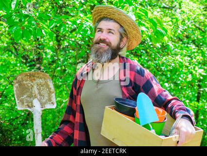 Glücklicher Bauer im Frühlingsgarten. Gärtner in Öko-Farm mit Gartengeräten Pflanzen. Mann mit Schaufel. Stockfoto