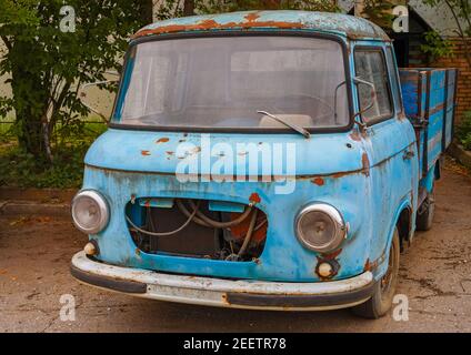 Ein altes faules blaues Auto mit einer Karosserie. Der LKW rostet auf der Straße. Stockfoto