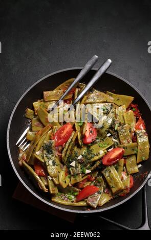 Bratpfanne mit grünen Bohnen und Gemüse auf dunklem Hintergrund. Taccole, Piattoni. Draufsicht. Stockfoto