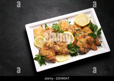 Hähnchenschnitzel auf einem weißen Teller. Dunkler Hintergrund. Draufsicht. Stockfoto