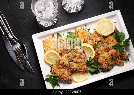 Hähnchenschnitzel auf einem weißen Teller. Dunkler Hintergrund. Draufsicht. Stockfoto