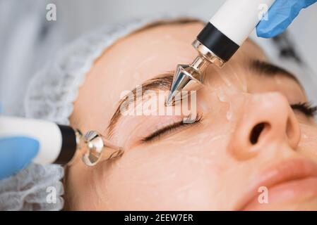 Straffung der Muskeln des Gesichts eines jungen schönen Mädchen mit Mikroströmungen. Stockfoto