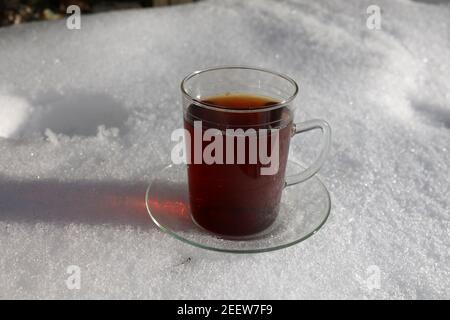 Ein Becher heißen Tees steht im Schnee. Stockfoto