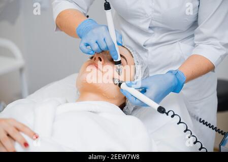 Doktor macht Gesichtsmassage zu einem jungen Mädchen mit Mikroströmungen. Stockfoto