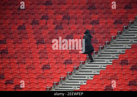 Budapest, Ungarn. Februar 2021, 16th. Fußball: Champions League, K.O.-Runde, Runde 16, erste Etappe, RB Leipzig - FC Liverpool in der Puskas Arena. Ein Fotograf geht auf dem leeren Stand. Kredit: Marton Monus/dpa/Alamy Live Nachrichten Stockfoto