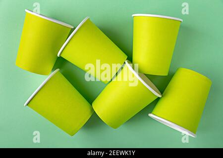 Viele grüne Pappbecher für Kaffee oder Tee zum Mitnehmen ohne Deckel, die dann recyclingfähig sind. Leere Nachbildung flach auf grünem Hintergrund liegen. Kein Abfall, pla Stockfoto