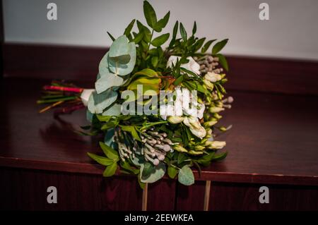 Brautstrauß mit weißen Blüten und grünen Zweigen auf braun Hintergrund Stockfoto