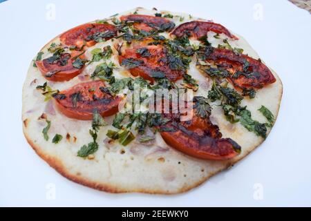 südindische Küche Uttapam, auch bekannt als Uttapa, ist ein indischer herzhafter Pfannkuchen. Belag von Tomatenscheiben, Koriander und Zwiebel. Das ist Tomato uttapam Stockfoto