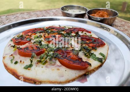 südindische Küche Uttapam, auch bekannt als Uttapa, ist ein indischer herzhafter Pfannkuchen. Belag von Tomatenscheiben, Koriander und Zwiebel. Das ist Tomato uttapam Stockfoto