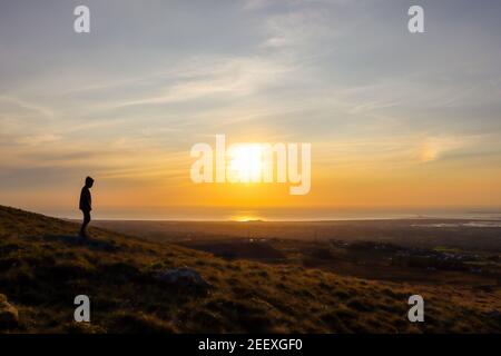 Mann Silhouette stehend beobachten Sonnenuntergang am Horizont, Rhosgadfan, Gwynedd, Snowdonia, North West Wales, VEREINIGTES KÖNIGREICH Stockfoto