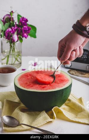 Der Löffel mit Stück Wassermelone in man Hand Stockfoto