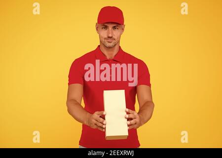 Service plus Qualität. Serious Kerl halten Paket gelben Hintergrund. Man Lieferservice. Express-Kurierdienst. Versand- und Lieferservice. Versand per Paketpost. Wert auf uns verlassen, kopieren Raum. Stockfoto