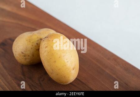 Nahaufnahme von zwei frischen Kartoffeln auf braunem Holz Platine Stockfoto