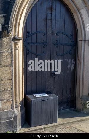 Eine Kiste für Spenden für eine Essensbank vor einer Kirchentür in Baildon, Yorkshire. Stockfoto