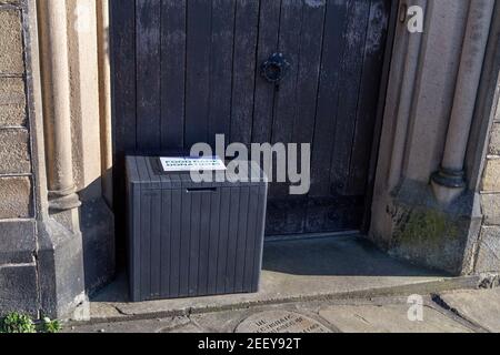 Eine Kiste für Spenden für eine Essensbank vor einer Kirchentür in Baildon, Yorkshire. Stockfoto