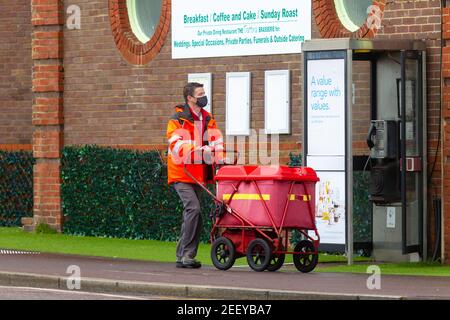 Royal Mail Lockdown Postbote trägt Gesichtsmask mit Trolley, großbritannien Stockfoto