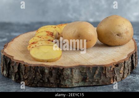 In Scheiben geschnittene und ganze Kartoffeln auf Holzbrett Stockfoto