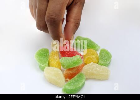 Hand Abholung einer roten Jujube Süßigkeiten von wenigen Jujubes Auf weißem Hintergrund Stockfoto