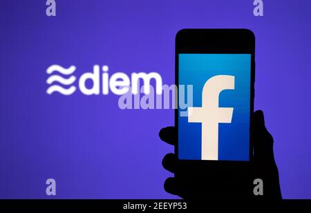 Silhouette des Smartphones mit Facebook auf dem Bildschirm und Facebook Diem Krypto-Münze Logo auf dem großen unscharfen Bildschirm. Echtes Foto, keine Montage, kein edi Stockfoto