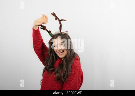 Lächelndes Mädchen trägt einen Weihnachts-Pullover und entzückende Hirsch Hörner Kopfband Stockfoto